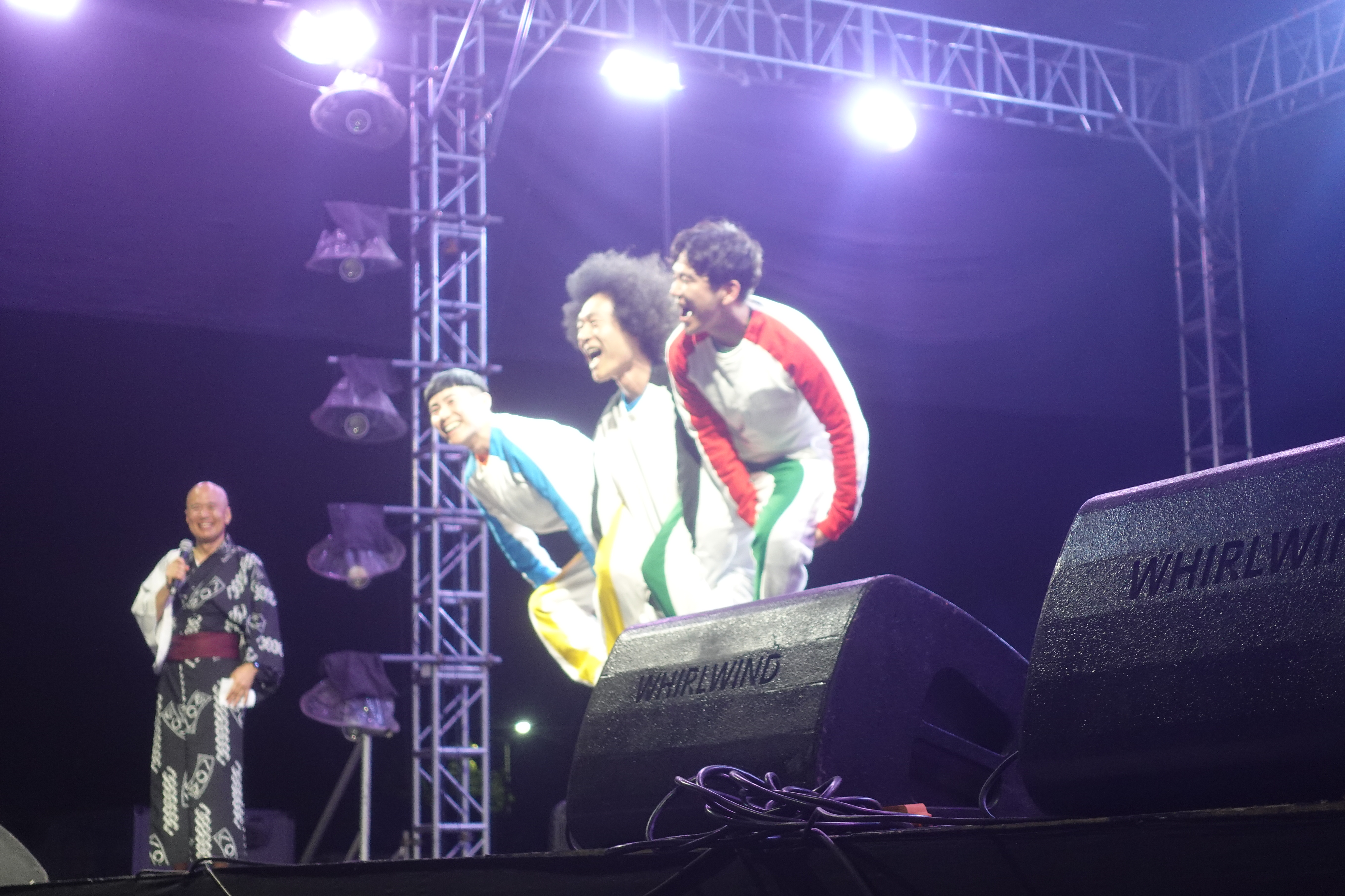 Performers on stage in traditional attire during Bon Odori festival, audience watching.