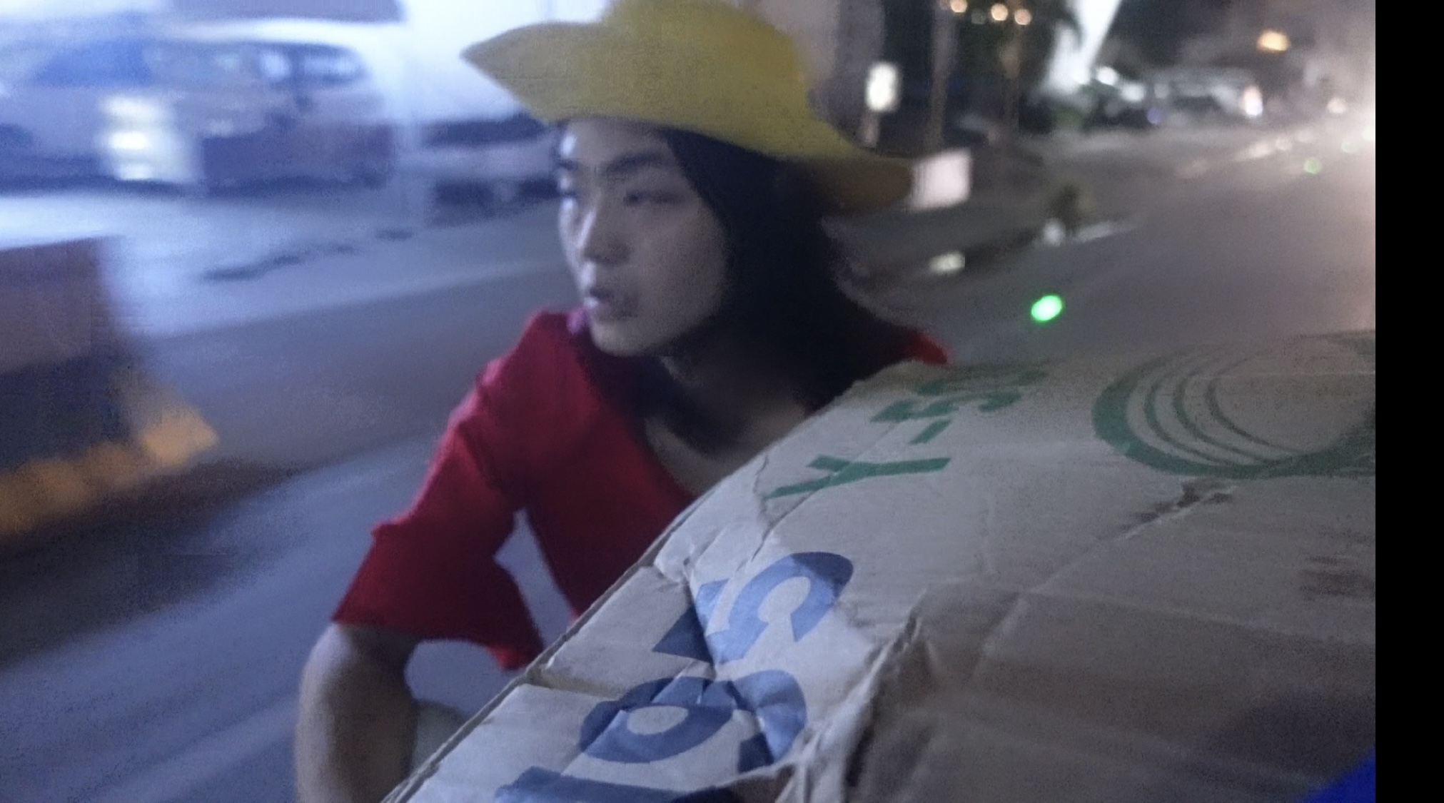 Person in red outfit riding in the back of a vehicle at night, looking forward.