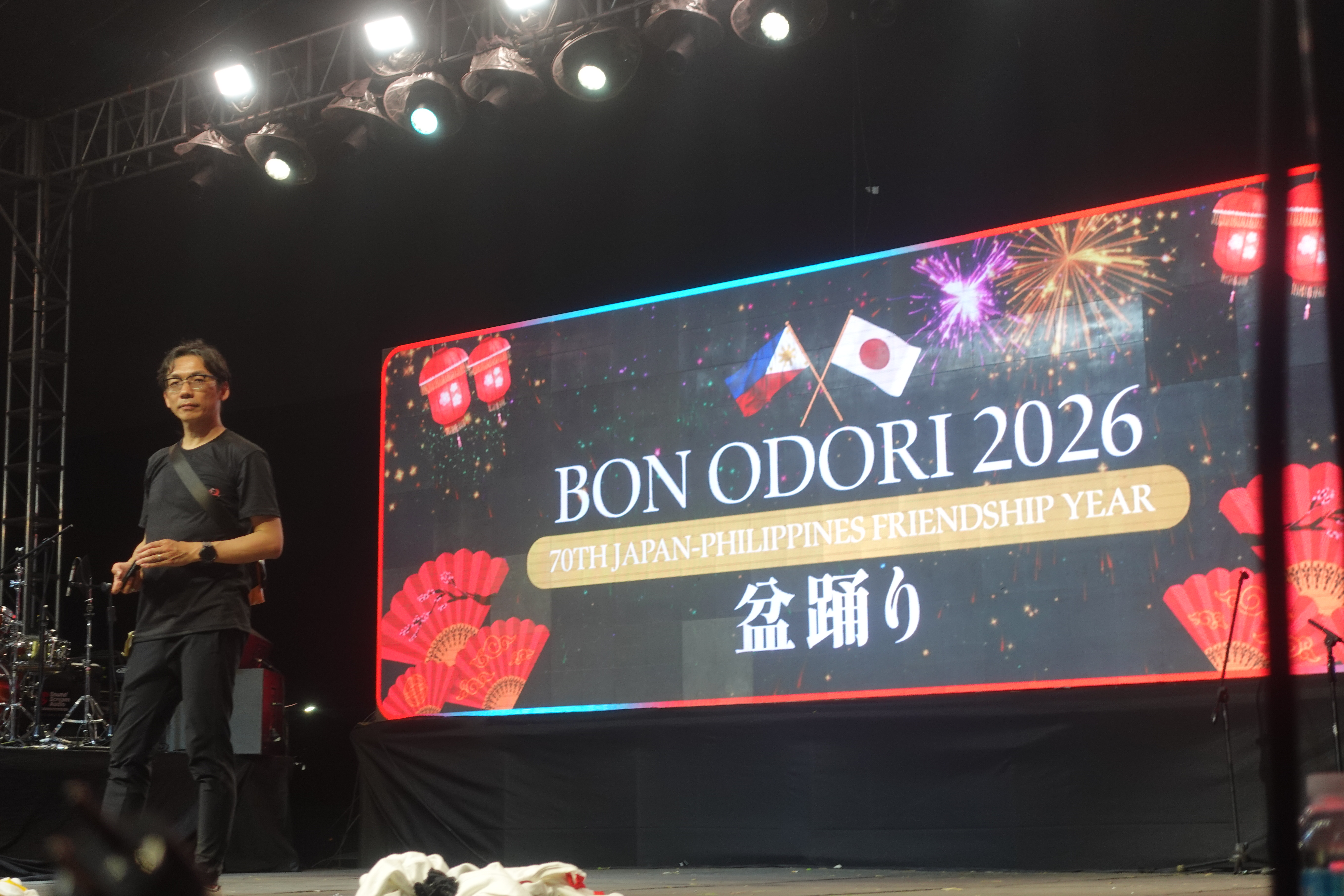 Festival stage with “BON ODORI 2026” banner, lights and audience visible.