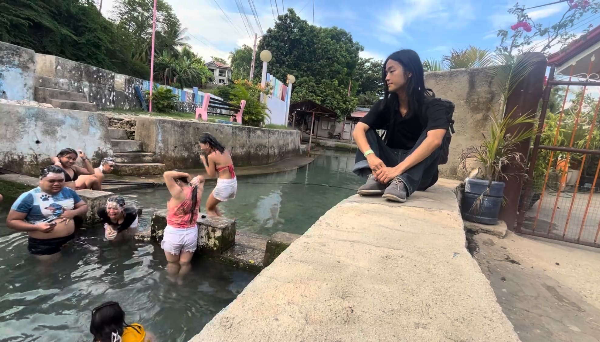 a guy looking at a cold spring while everyone is enjoying the water