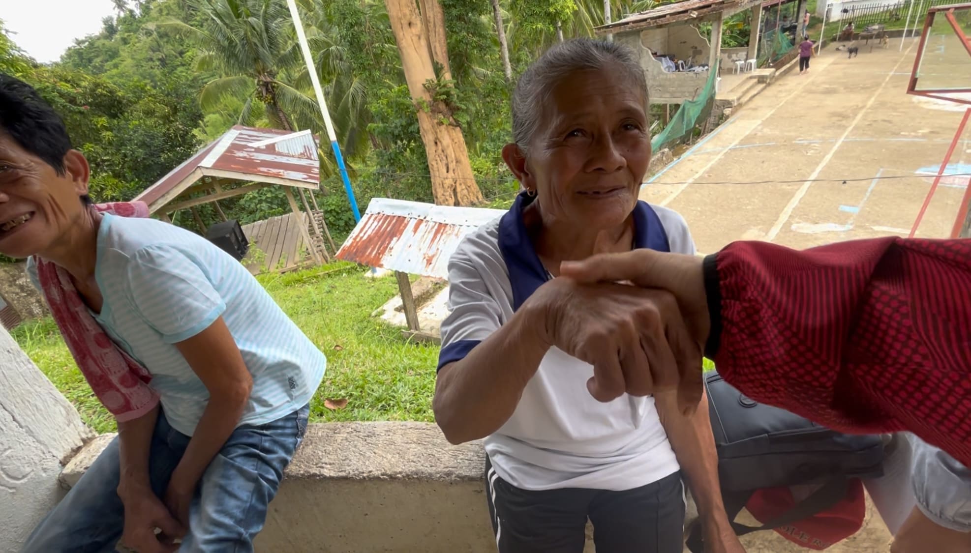 An elderly woman smiling and saying Balik during farewell