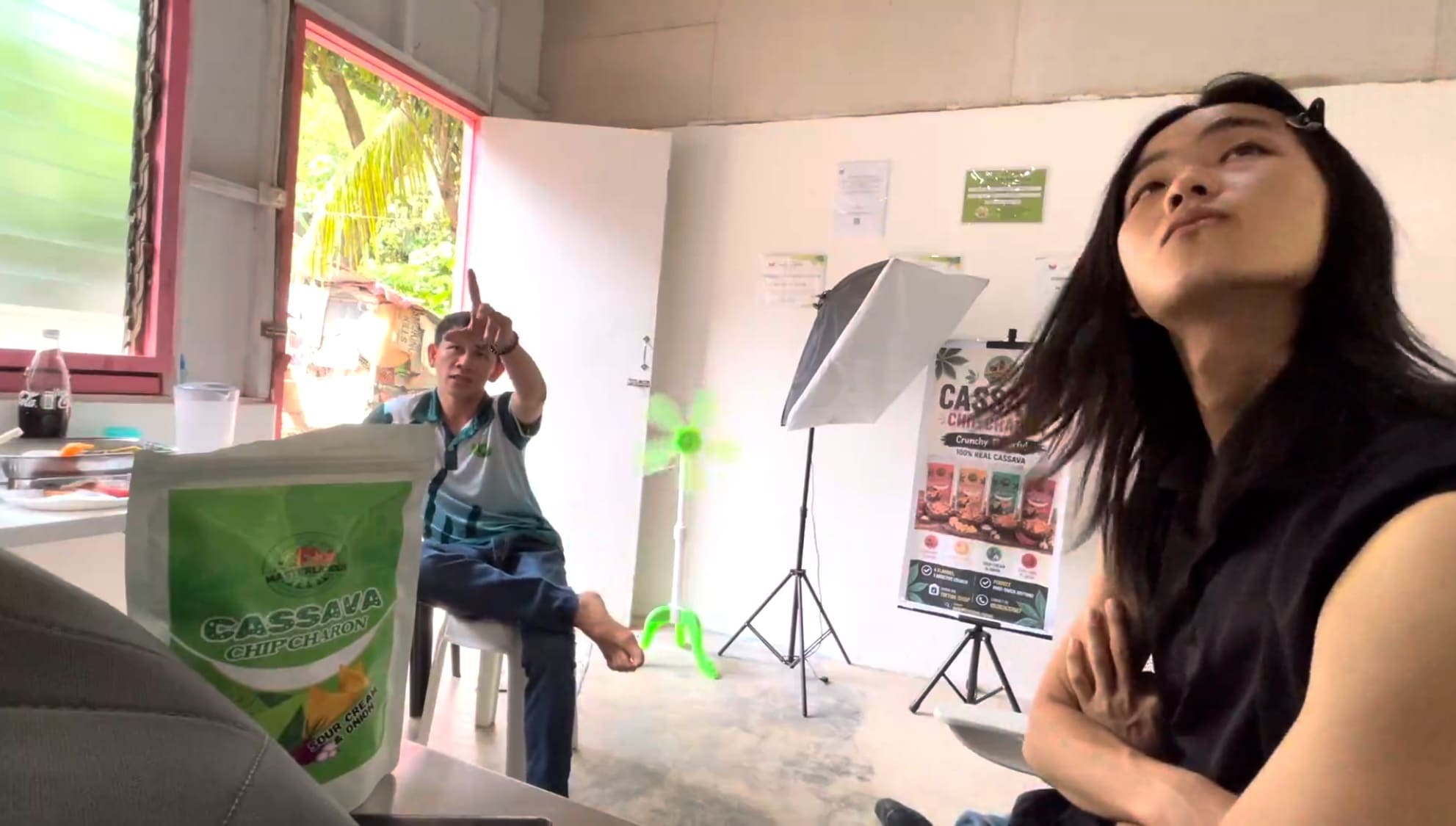 Man pointing at the Masterlicious Foods brand name on a wall while another man looks surprised