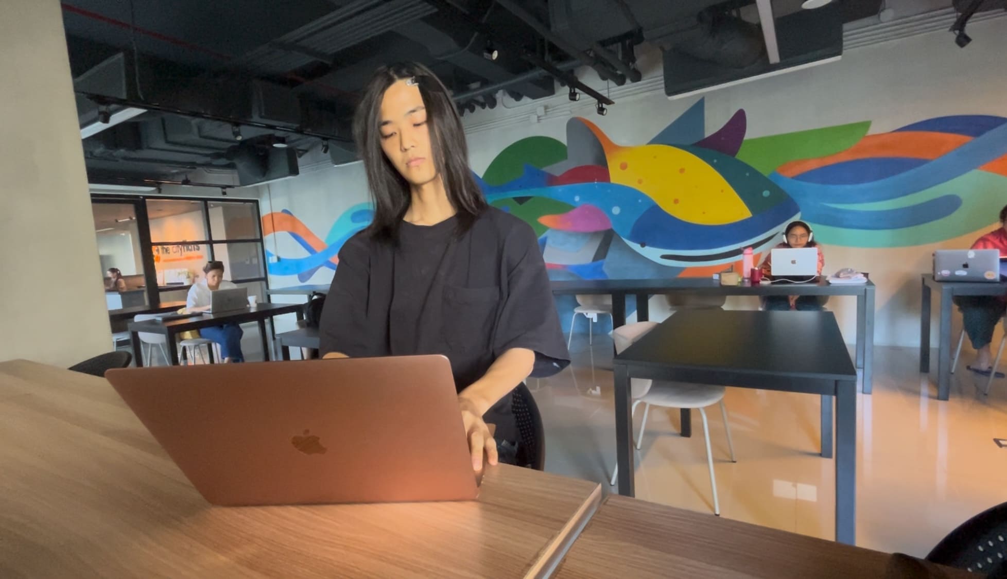 Man closing a laptop at a coworking space before heading out