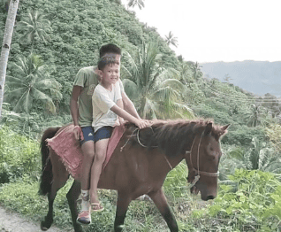 A kid and an adult riding a horse together