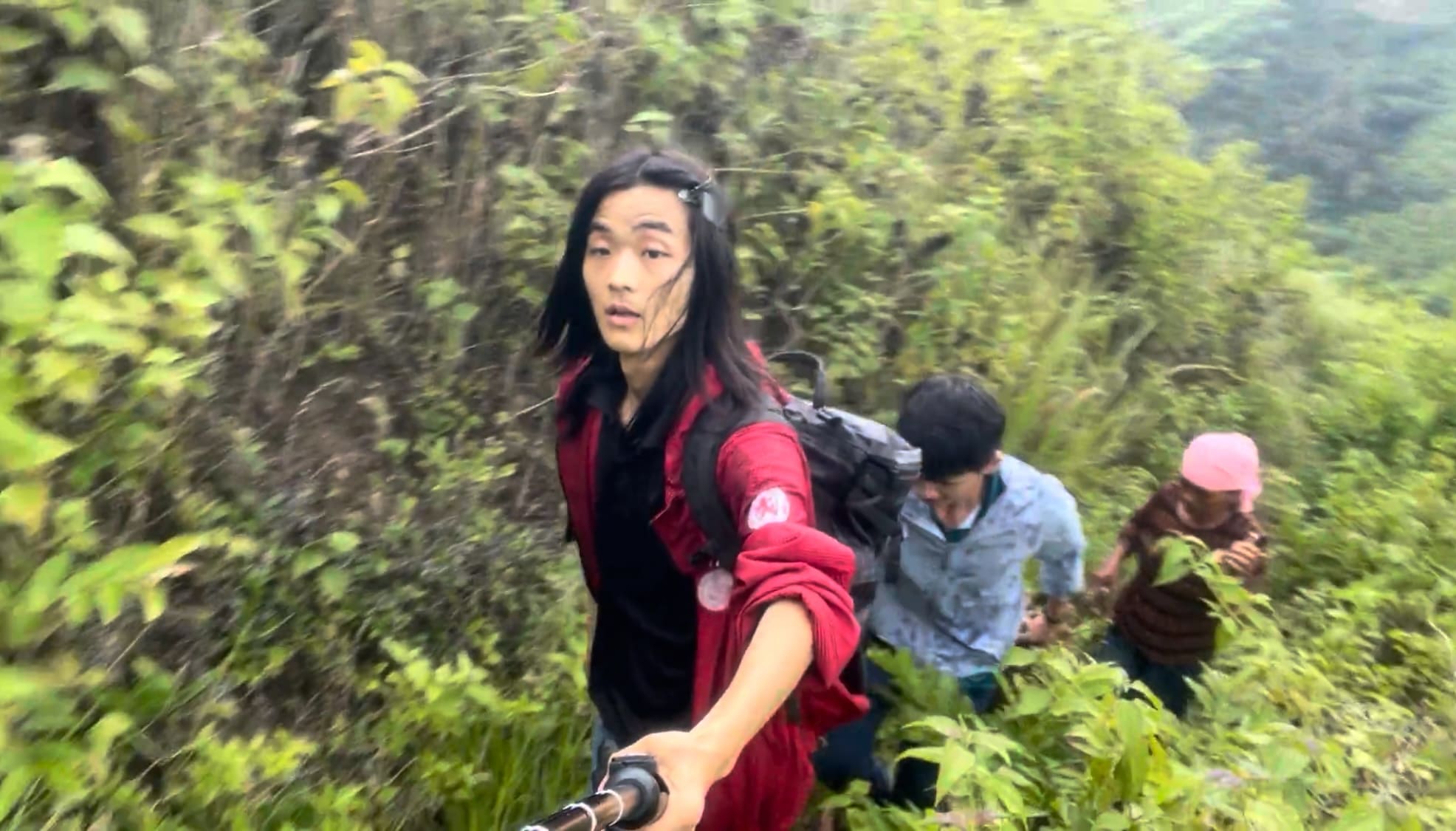 Two men and a woman walking along a mountain road