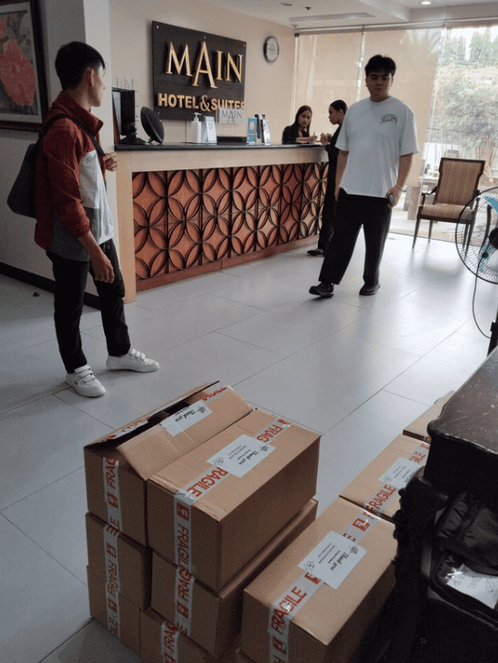People and cardboard boxes filled with cassava chips at a hotel entrance