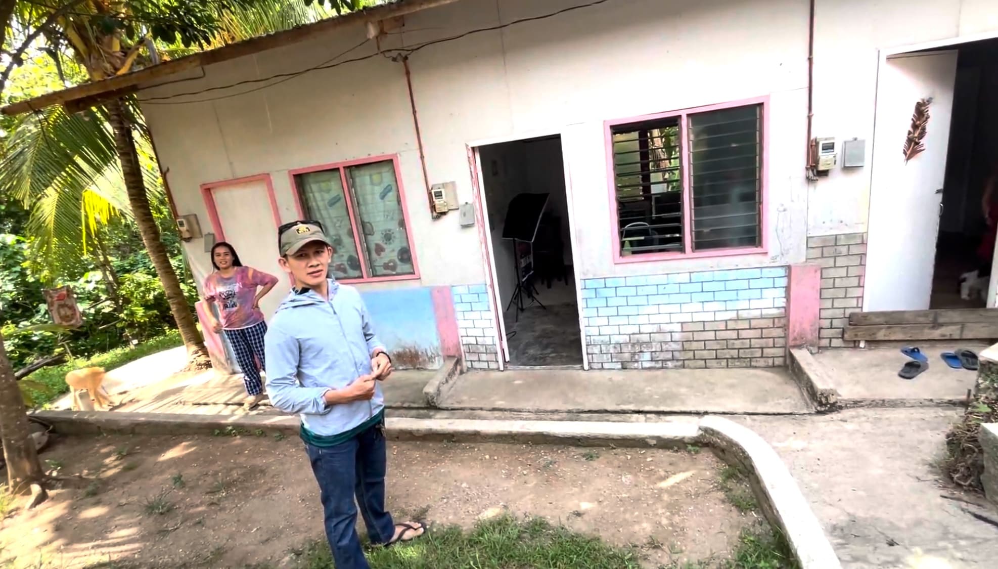 A man standing in front of a two-room boarding house used as a cassava processing facility in Catmon, Cebu