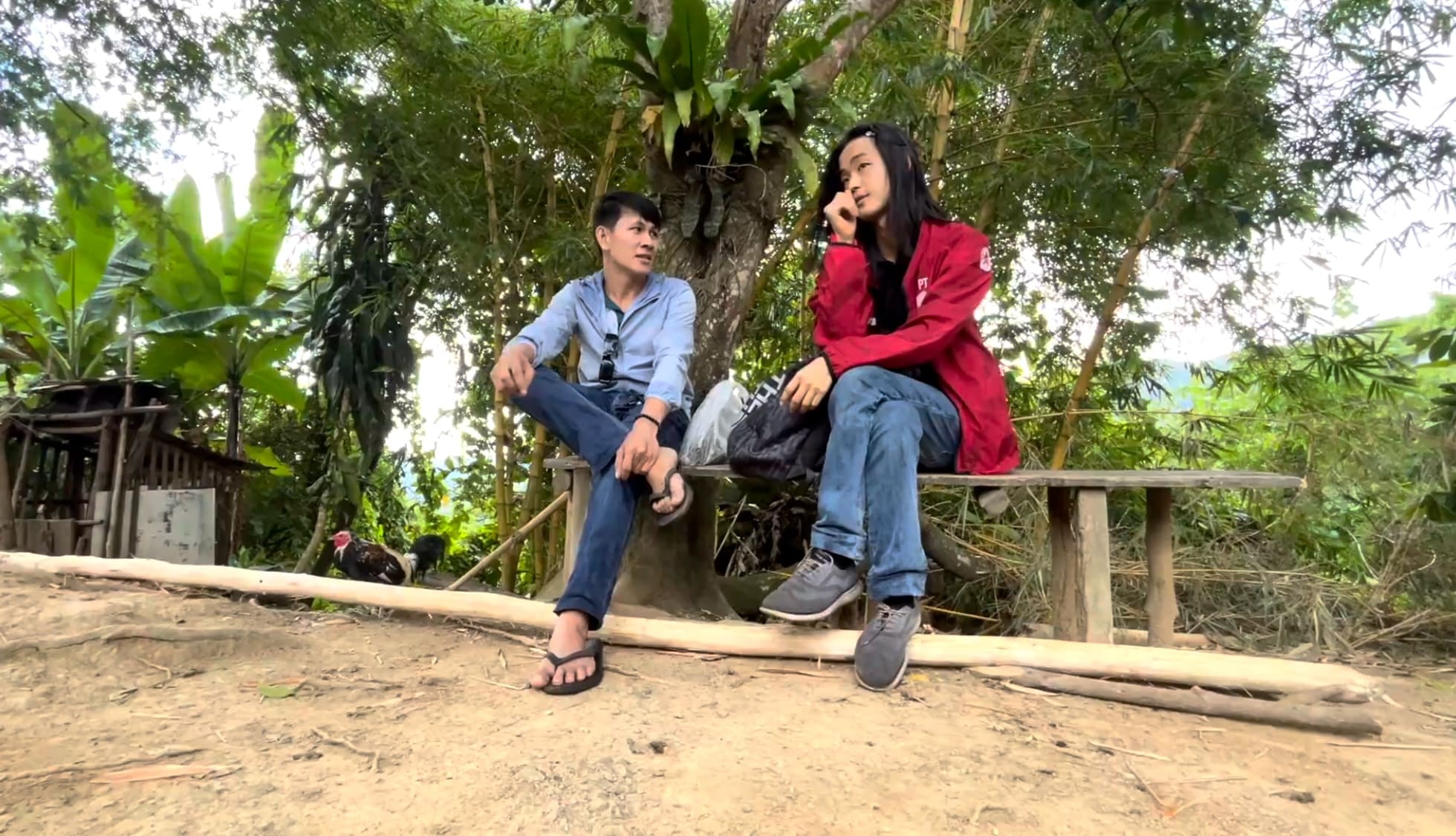Two men talking outside on a bench in a rural mountain area