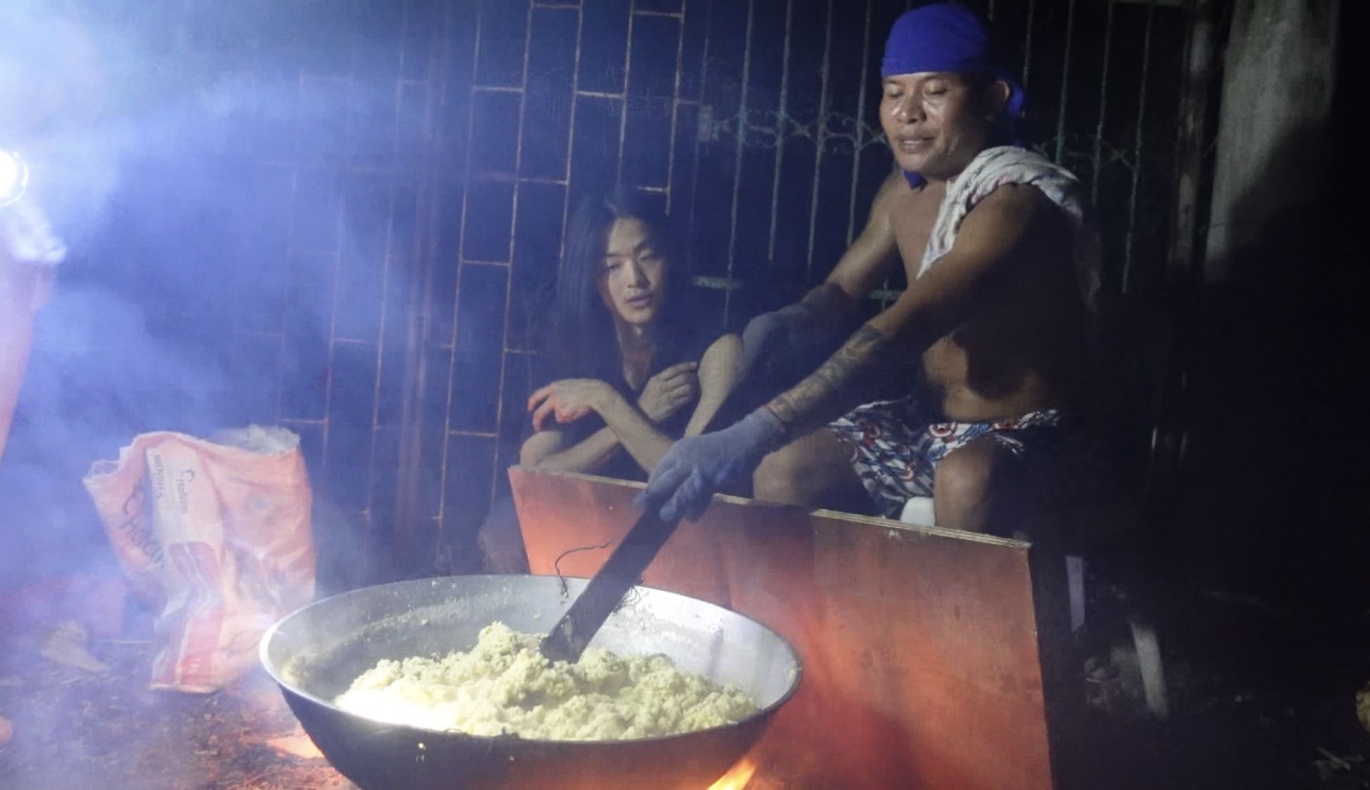Man making Budbud Kabog while another man documents the process
