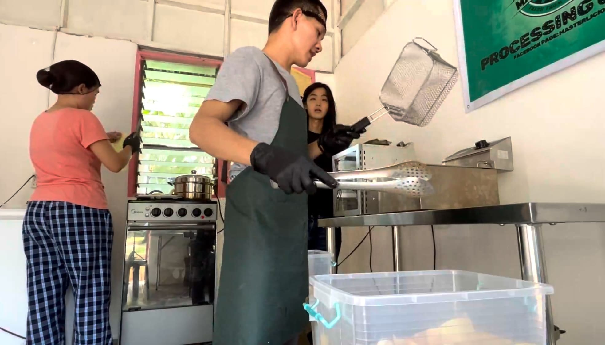 Man frying cassava chips while another man watches