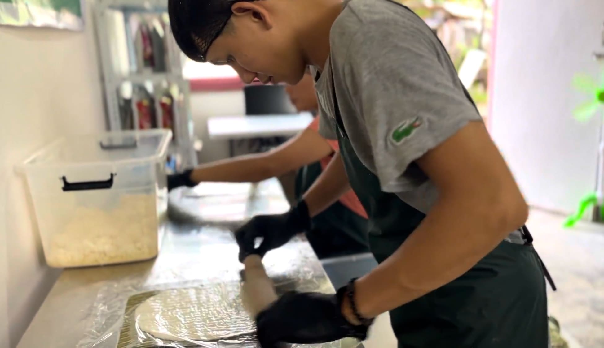 Man flattening cassava dough by hand during food production