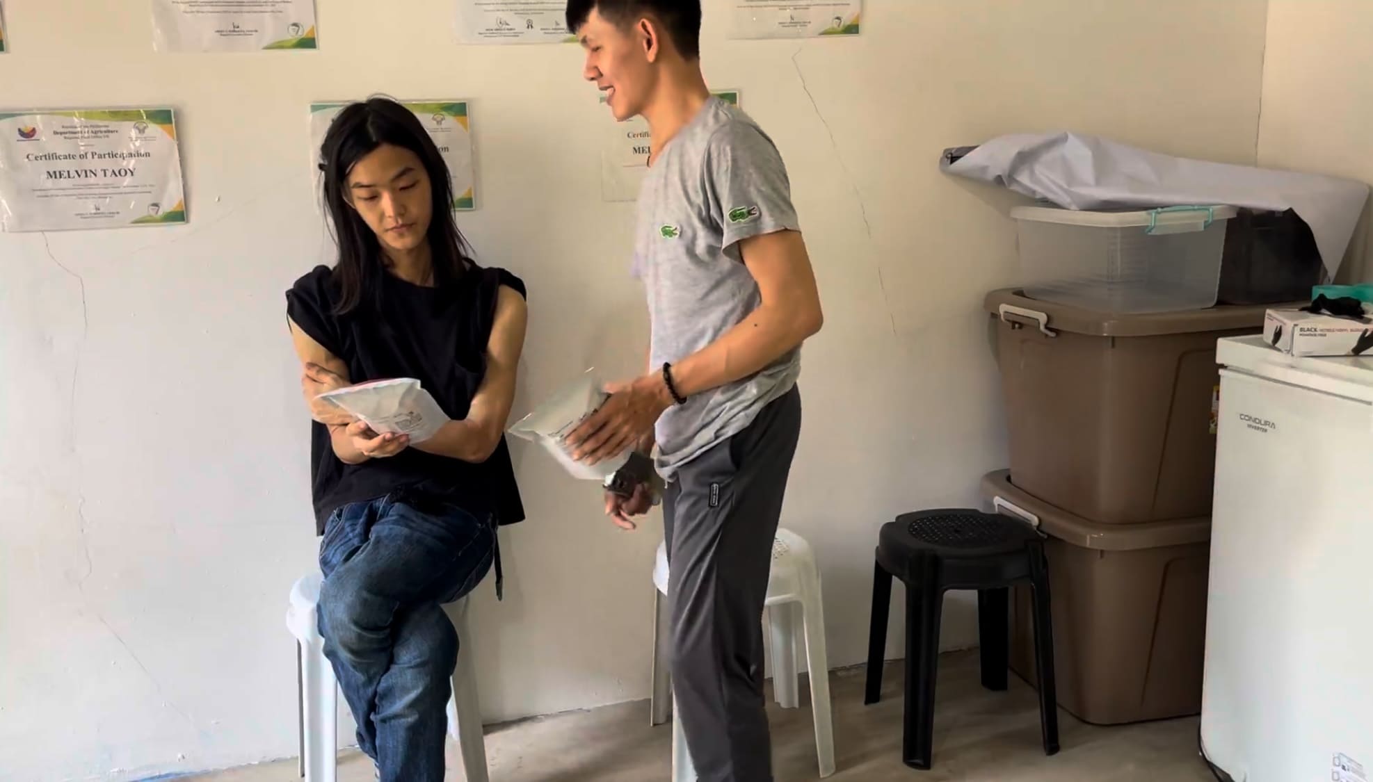 Man checking a cassava chipcharon package while another man watches