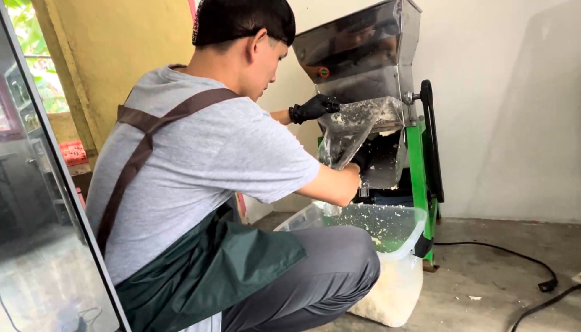 Man collecting cassava from a grating machine at a small processing facility