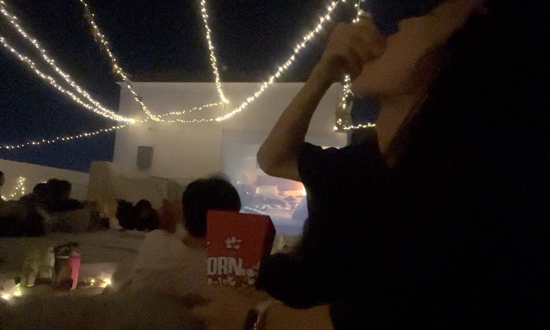 Man eating free popcorn from staff at a Cinema Night on a rooftop deck