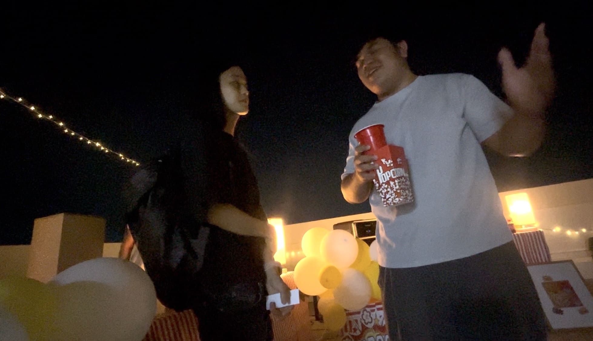 Two men talking during a Cinema Night on a rooftop deck