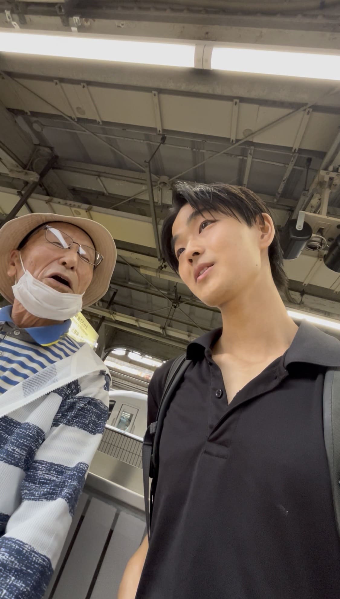 Young man talking with an elderly man on a station platform