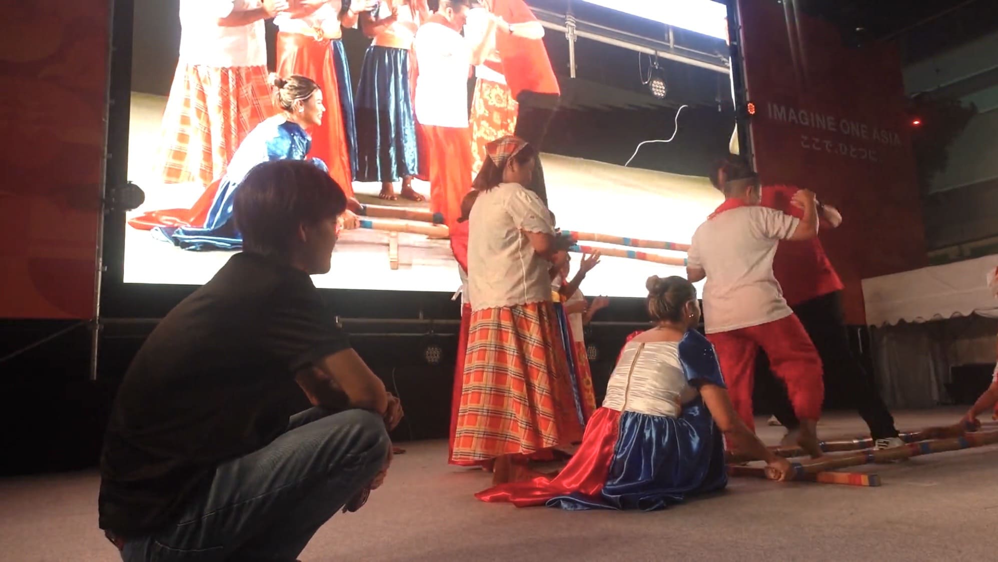 Man watching a Filipino bamboo dance performance up close at Oasis 21