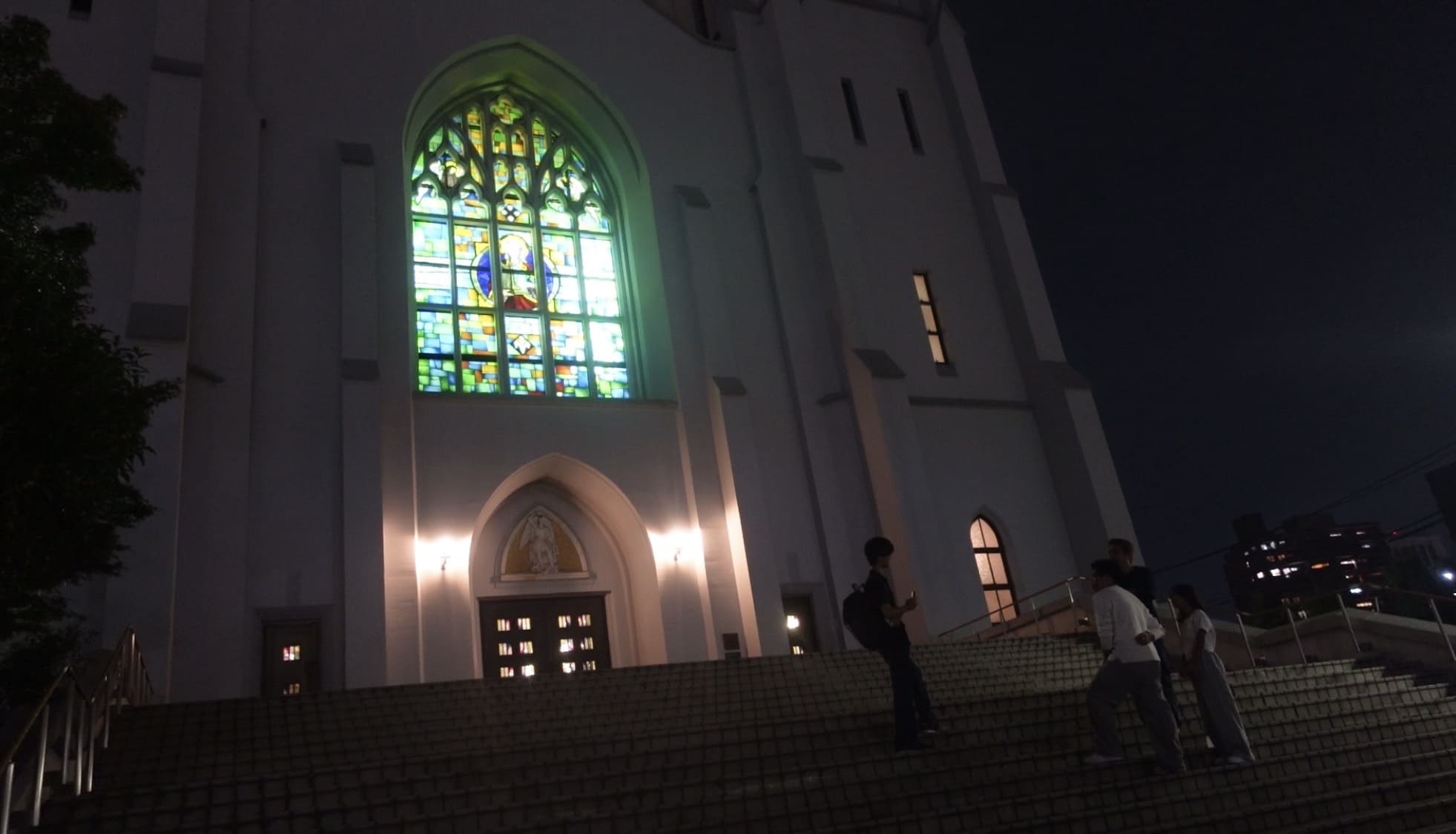 A man and two Filipino men talking outside Nunoike Church in Nagoya at night
