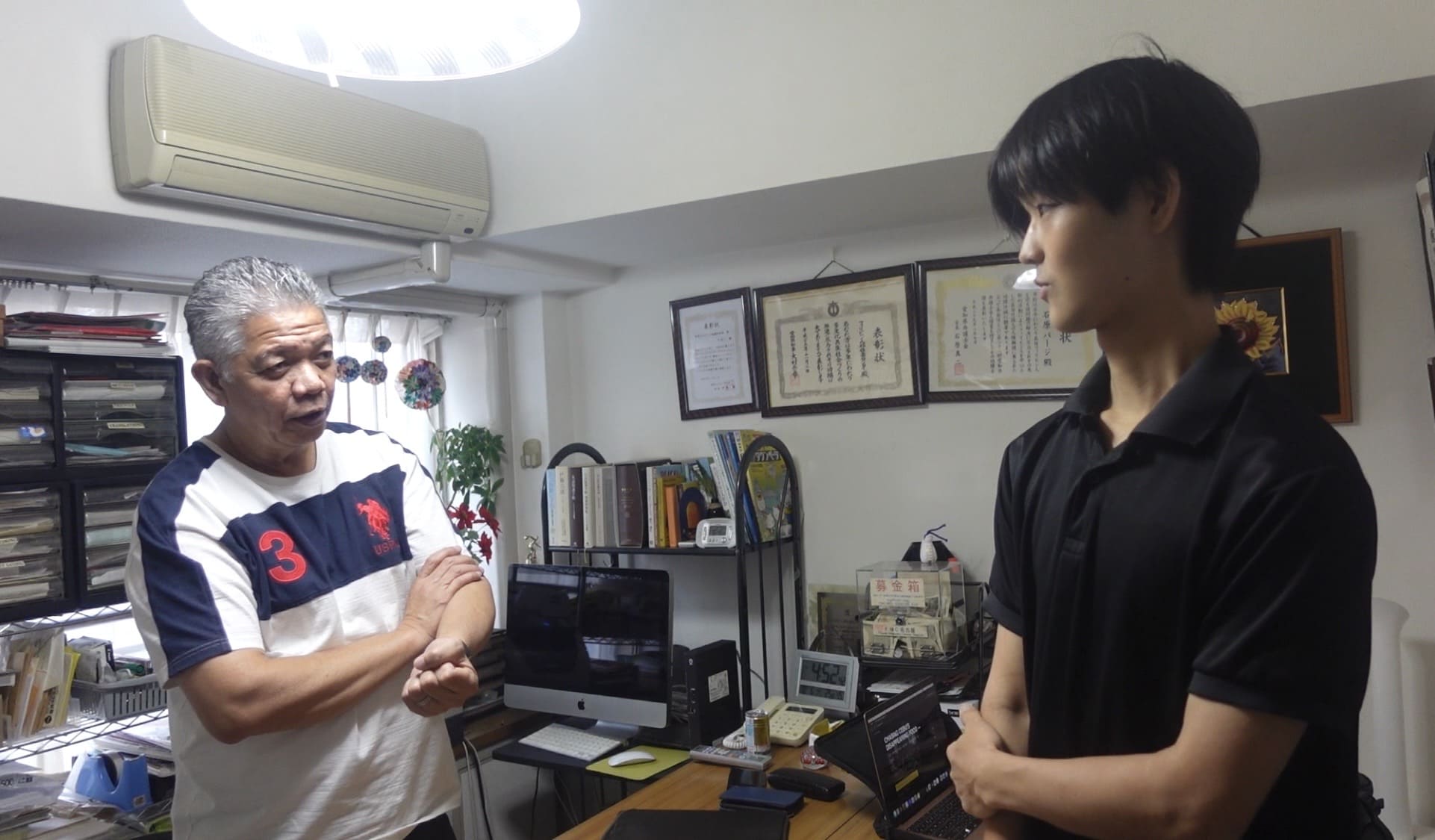 Two men standing face to face and talking inside a community office