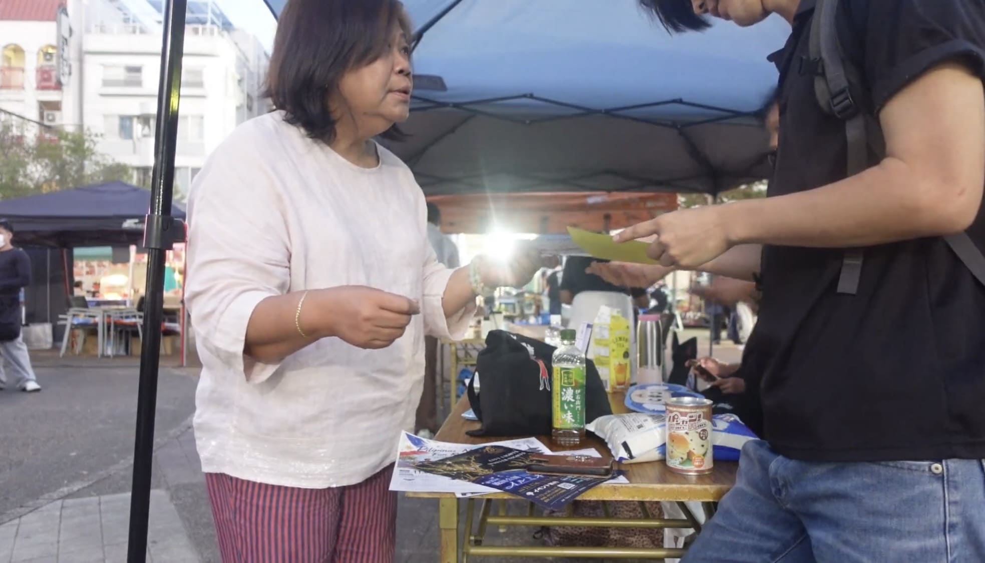 Filipino woman speaking with a man and handing him a leaflet during an interview