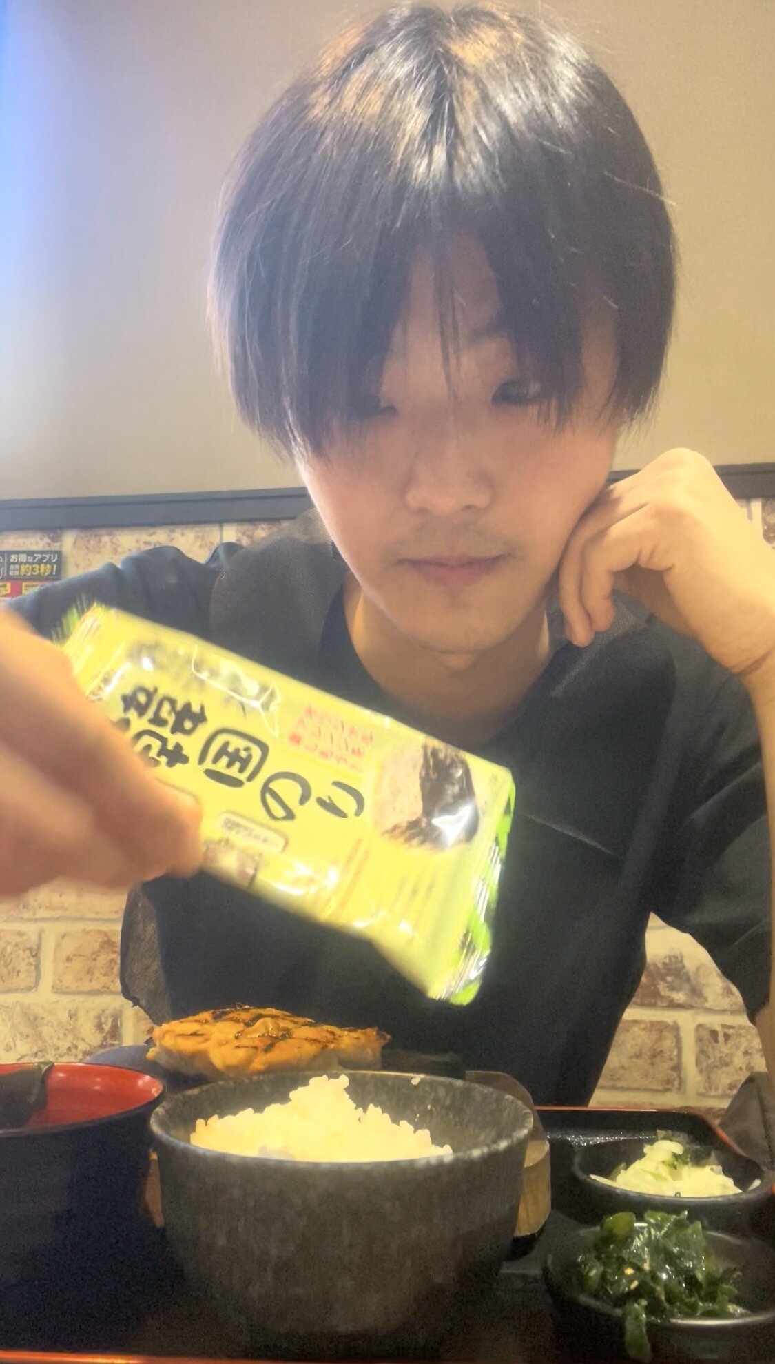 A man looking surprised at a table full of rice, kimchi, miso soup, vegetables and Korean seaweed