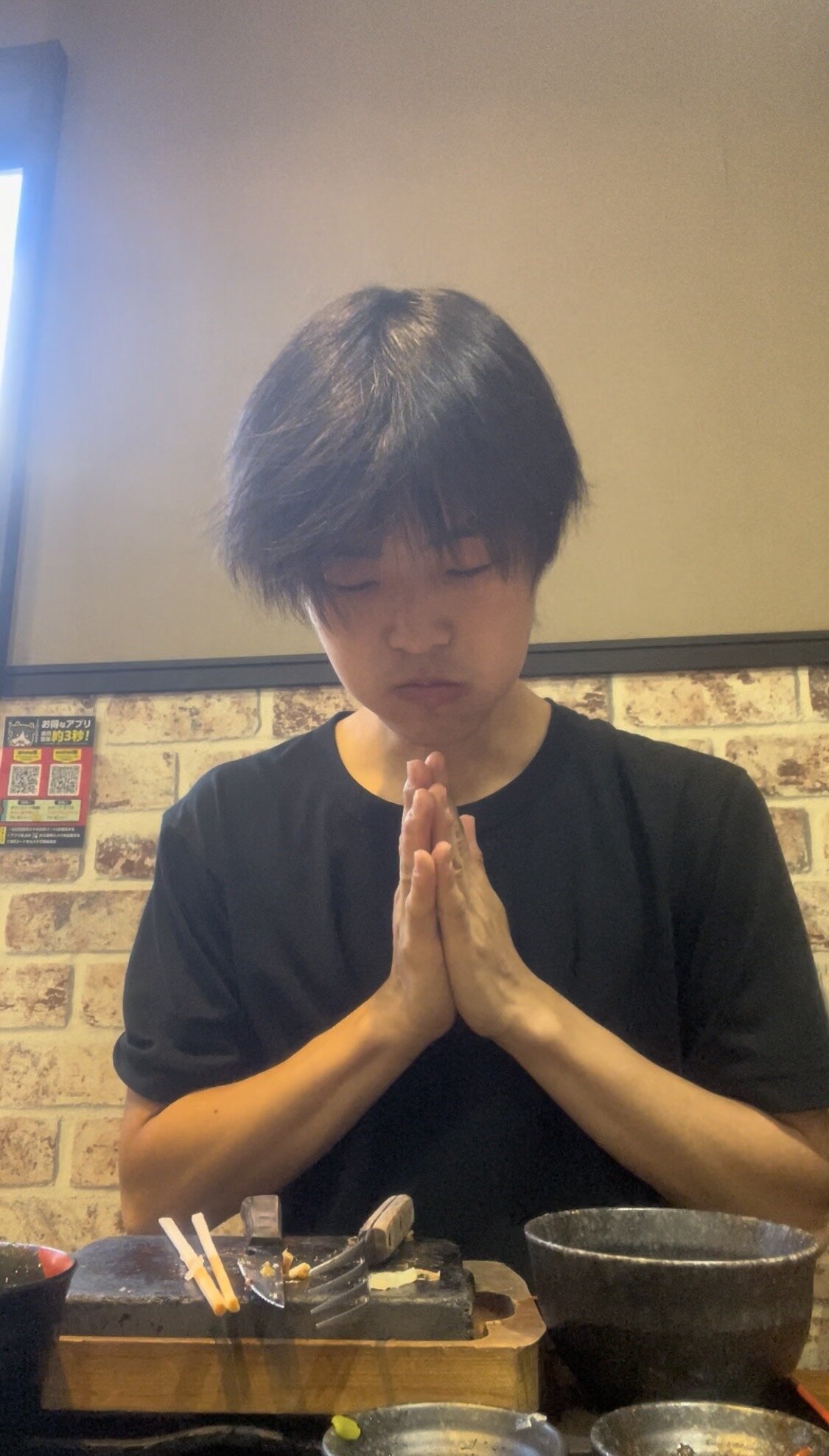 A man putting his hands together to say thanks after finishing a meal